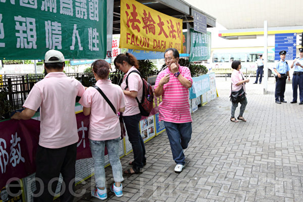 穿着粉红色制服的“香港青年关爱协会”中共帮凶在绑横幅，负责人林国安在旁指挥。（摄影：潘在殊／大纪元）