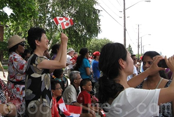 图：拿着2个小国旗的唐女士说：“每年的游行都是法轮功的队伍最壮观！”（摄影：张莹/大纪元）