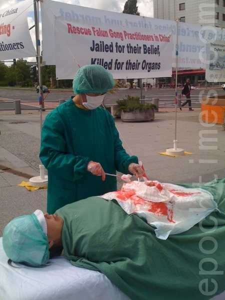在国际器官移植会议开会地点前，法轮功学员演示中共活体摘除器官。（摄影：刘成/大纪元）