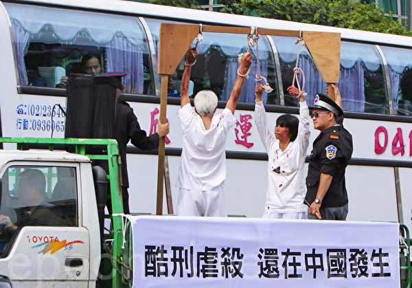 游行队伍的“酷刑演示”，吸引游览车里的旅客们关注。（摄影：林伯东／大纪元）