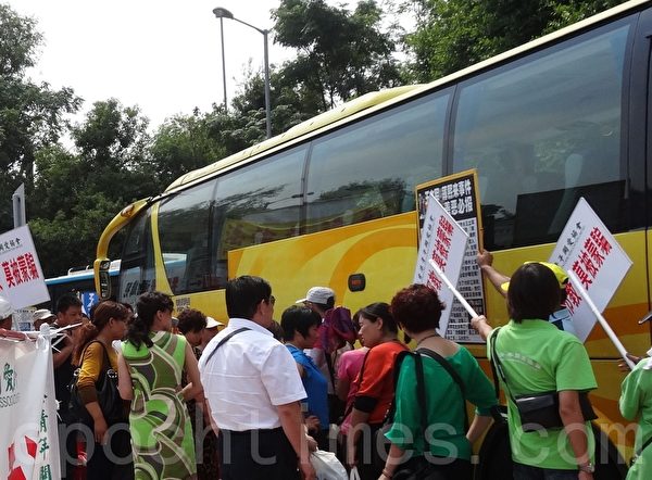 中港边境落马洲，中共恶党团伙“香港青年关爱协会”穿绿衣制服的成员阻档法轮功学员向来港游客讲真相。（市民提供）