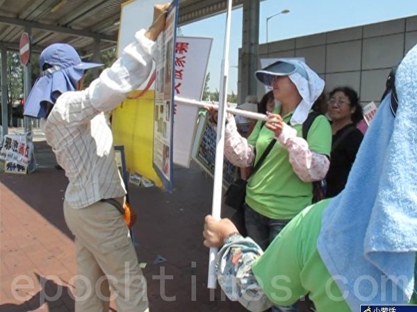 图为9月16日青关会团伙（绿衣）阻止法轮功学员（左一）以展板向大陆游客讲真相。（大纪元）