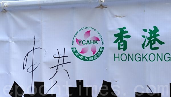 有市民在青关会诬蔑法轮功的横幅上，写上“中共”，表达青关会不代表香港，而是中共政法委在香港的爪牙。（摄影：宋祥龙／大纪元）