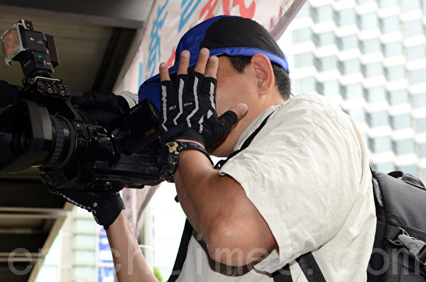 在曾庆红、梁振英授意下，青关会雇佣配备专业摄影器材来滋扰香港法轮功真相点的帮凶。（大纪元图片）