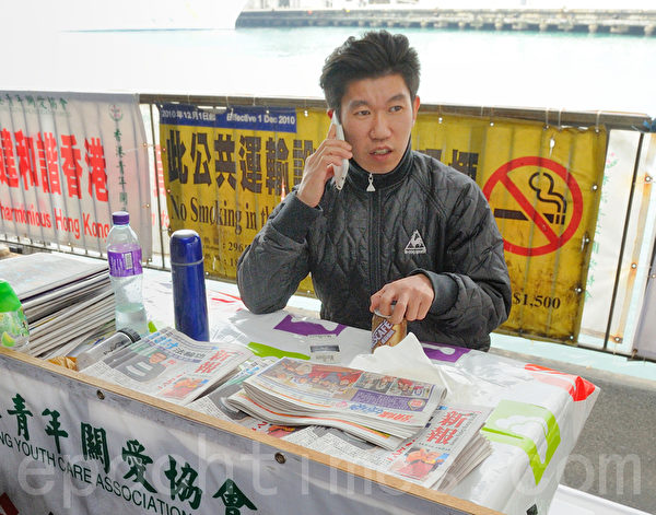 这名青关会成员声称是“义工”，看守在香港天星码头的档口，派发污蔑法轮功的报刊《新报》，《新报》的老板是香港富商杨受成。（大纪元图片）