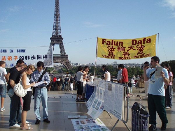 图为到法国的游客在法轮功真相点上了解中共迫害法轮功真相。（大纪元）