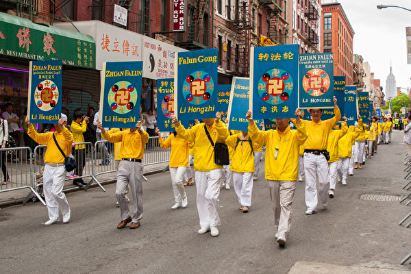 2013年5月18日，紐約曼哈頓，來自世界各地的法輪功學員在此舉行慶祝法輪大法弘傳21週年大遊行。圖為遊行的第一主題「大法洪傳」方陣，《轉法輪》大型展板。（攝影：陳虎/大紀元）