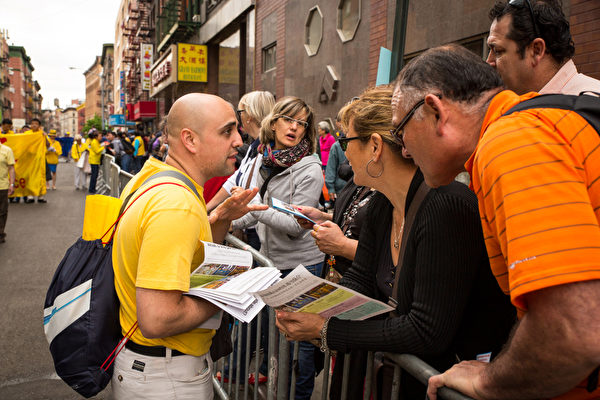 2013年5月18日，紐約曼哈頓，來自世界各地的法輪功學員在此舉行慶祝法輪大法弘傳21週年大遊行。圖為圍觀民眾拿傳單並聽法輪功學員（左）講真相。（攝影：陳虎／大紀元）