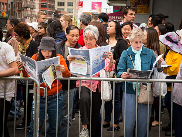 2013年5月18日，紐約曼哈頓，來自世界各地的法輪功學員舉行慶祝法輪大法弘傳21週年大遊行。圖為圍觀民眾正在閱讀法輪功真相資料。（攝影：陳虎／大紀元）