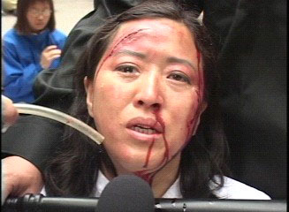 正在演示酷刑的王玉芝女士，含泪诉说被中共劳教所折磨的亲身经历。