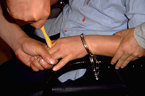 中共黑獄酷刑演示：牙刷鑽指縫。（圖片來源：明慧網）
