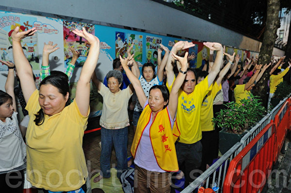 香港法輪功學員在中聯辦後門對面馬路集會，平和演示法輪功的五套功法。（攝影：宋祥龍／大紀元）