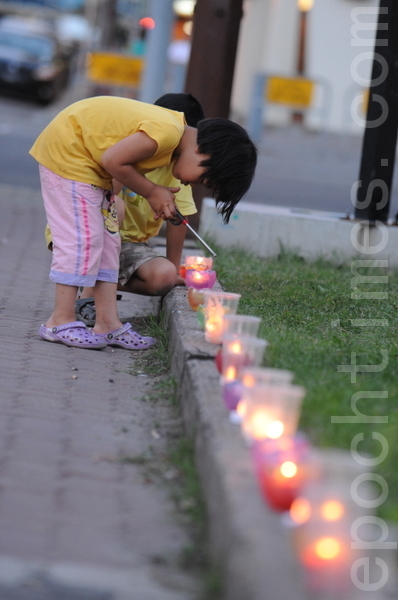 图：2013年7月20日晚上，卡尔加里部分法轮功学员在中共领事馆前静坐，纪念7.20十四周年。图为大法小弟子在点燃蜡烛。（吴伟林/大纪元）