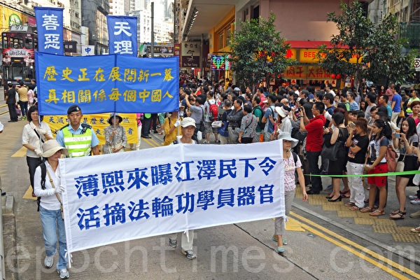 香港国殇日的集会结束后，800名游行人士手持各式横幅幡旗，从北角英皇道游乐场出发前往中共驻港联络办事处，浩浩荡荡的游行队伍吸引大批中港人士驻足观看。（潘在殊／大纪元）