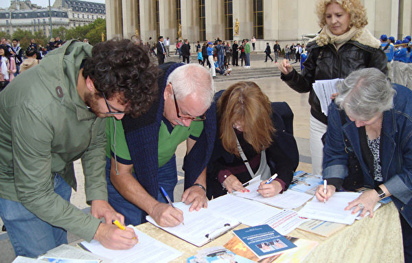 各國遊客爭先在制止中共活摘器官的征簽簿上簽字。（攝影：黎平/大紀元）