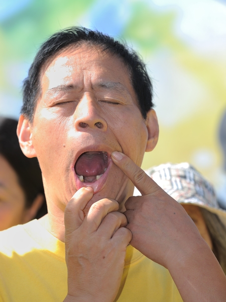2013年10月20日，洛杉矶，集会上法轮功学员展示牙齿被中共恶警打掉。（宋祥龙/大纪元）