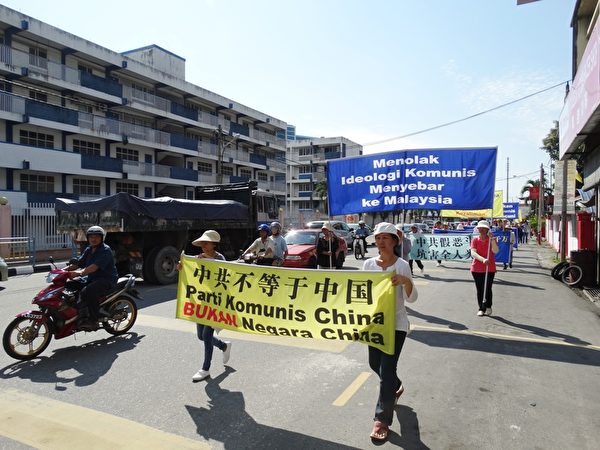 参与游行的义工们手持多幅横幅，声援三退的同时也提醒国人共产党的邪恶本质，引起许多民众和驾驶人士的关注。（杨晓慧/大纪元）