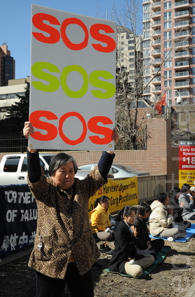 在喧嚣的市中心第六大道的人行道上，黄金玲女士静静地高举着SOS字样的牌子，站在中共领事馆前，向国际社会发出求救的呼声：“救救我女儿”!（吴伟林/大纪元）