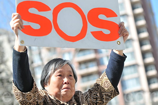 女儿绝食已经32天，生命垂危。黄金玲女士高举SOS牌子，站在中共领事馆前，向国际社会发出求救的呼声：“救救我女儿”!（吴伟林/大纪元）