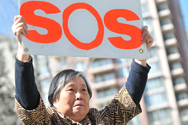 圖：4月16日，加拿大公民黃金玲女士已經第三天來到加拿大卡爾加里中共領事館前，高舉SOS牌子，向國際社會發出求救：「救救我女兒」！（吳偉林 /大紀元）