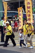 香港法輪功學員4月20日舉行聲勢浩大的遊行，紀念「四．二五」和平大上訪15周年，大約八百人遊行隊伍沿著九龍的鬧市區，途經多個大陸遊客購物熱點，吸引兩旁的大批遊客觀看，許多人拿著手機和相機爭相拍攝。（潘在殊／大紀元）