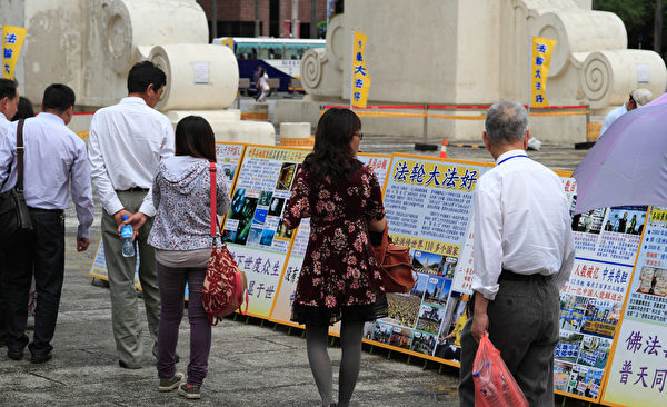 2014年4月26日，台湾法轮功学员于台北中正纪念堂、自由广场进行排字活动，并对来往民众洪法、讲真相。图为民众正在专心阅读展板。（罗正恒／大纪元）