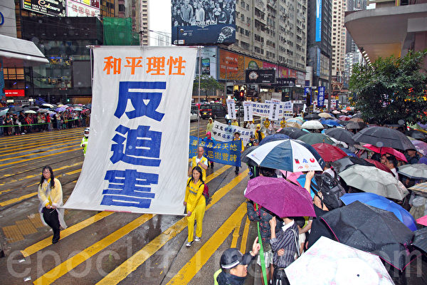 六百多名香港及來自亞洲地區的法輪功學員5月10日冒雨遊行，慶祝法輪大法洪傳世界22週年，希望將法輪大法的美好傳給世人，並呼籲民眾三退「解體中共」，制止中共活摘人體器官等暴行。聲勢浩大的遊行隊伍途徑港島的鬧市區，吸引許多市民和大陸遊客撐著傘在路旁觀看。（潘在殊/大紀元）