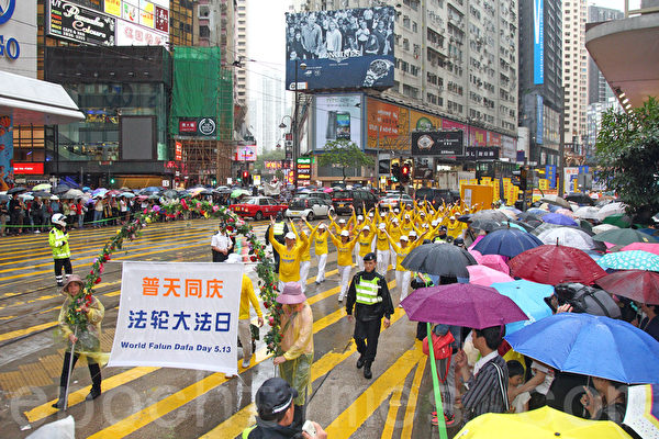 六百多名香港及來自亞洲地區的法輪功學員5月10日冒雨遊行，慶祝法輪大法洪傳世界22週年，希望將法輪大法的美好傳給世人，並呼籲民眾三退「解體中共」，制止中共活摘人體器官等暴行。聲勢浩大的遊行隊伍途徑港島的鬧市區，吸引許多市民和大陸遊客撐著傘在路旁觀看。（潘在殊/大紀元）
