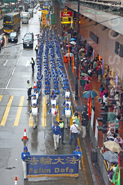 六百多名香港及來自亞洲地區的法輪功學員5月10日冒雨遊行，慶祝法輪大法洪傳世界22週年，希望將法輪大法的美好傳給世人，並呼籲民眾三退“解體中共”，制止中共活摘人體器官等暴行。聲勢浩大的遊行隊伍途徑港島的鬧市區，吸引許多市民和大陸遊客撐著傘在路旁觀看。（潘在殊/大紀元）