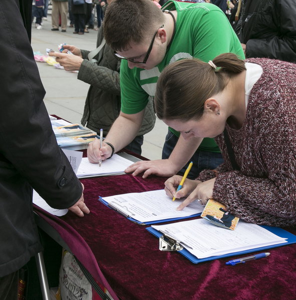 人們在簽名版上簽名，支持法輪功學員們反迫害的義舉。（羅元/大紀元）
