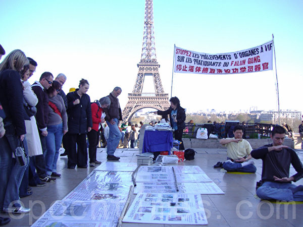 在世界各國的著名景點及繁華地帶都能見到法輪功學員義務在講真相。圖為到法國巴黎，遊客在法輪功真相點上了解中共迫害法輪功真相。（大紀元）