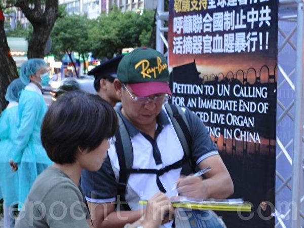 2013年8月24日，台湾台北，法轮功学员举办反活摘器官行动剧，吸引经过的行人驻足观看，民众了解中共残暴后，纷纷签名连署反中共活摘器官。（唐宾/大纪元）
