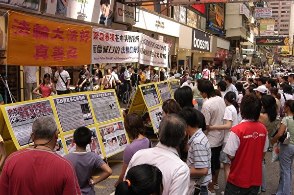 有越來越多民眾了解了共產黨的邪惡，在全世界範圍內掀起了退出中共的熱潮。圖為香港旺角街頭的真相點，令人震撼的迫害酷刑圖片，吸引民眾停下腳步圍觀。（李明/大紀元）。