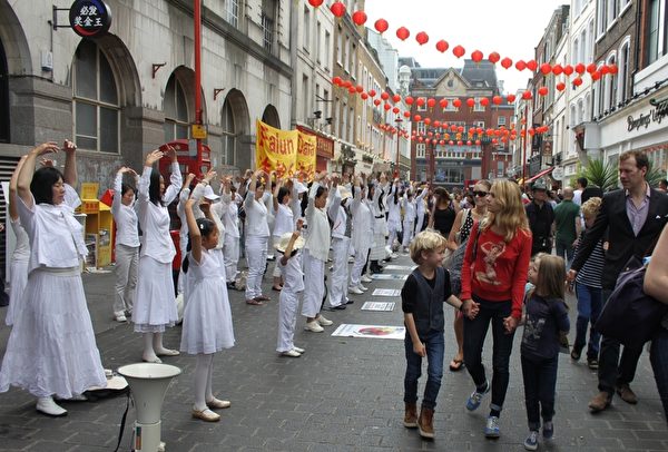 2014年7月12日，来自英国各地的法轮功学员，在伦敦市游行，呼吁善良民众伸出援手，共同结束中共对法轮功的迫害。图为游行队伍在中国城炼功。（李景行/大纪元）