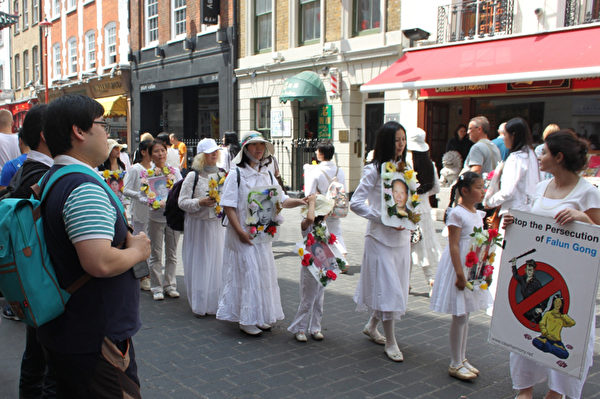 2014年7月12日，来自英国各地的法轮功学员，在伦敦市游行，呼吁善良民众伸出援手，共同结束中共对法轮功的迫害。图为游行队伍来到中国城。（李景行/大纪元）