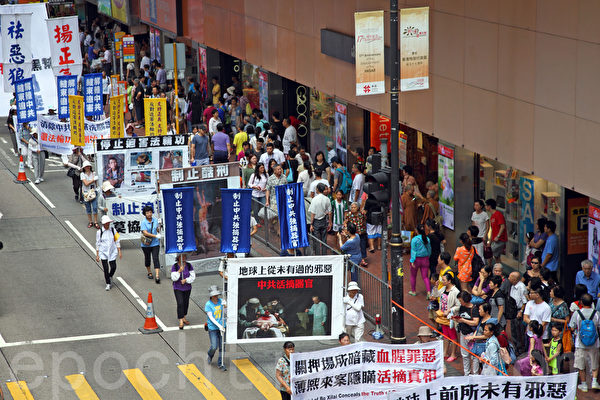 2014年7月19日，逾九百名法轮功学员在香港港岛区举行7.20十五周年反迫害集会游行，呼吁各界制止中共迫害法轮功。队伍从北角英皇道出发，途径多个闹市区抵达政府总部，吸引众多中港民众和游客驻足观看。（潘在殊／大纪元）