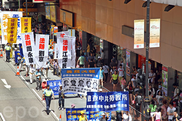 2014年7月19日，逾九百名法輪功學員在香港港島區舉行7.20十五周年反迫害集會遊行，呼籲各界制止中共迫害法輪功。隊伍從北角英皇道出發，途徑多個鬧市區抵達政府總部，吸引眾多中港民眾和遊客駐足觀看。（潘在殊／大紀元）