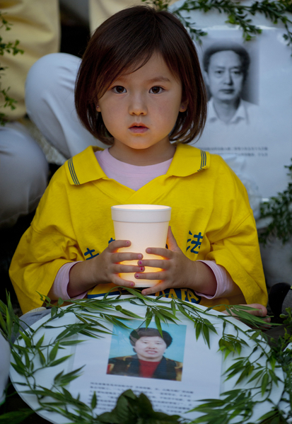 圖：一名小女孩，手持蠟燭悼念被中共迫害致死的法輪功學員。（大紀元圖片）