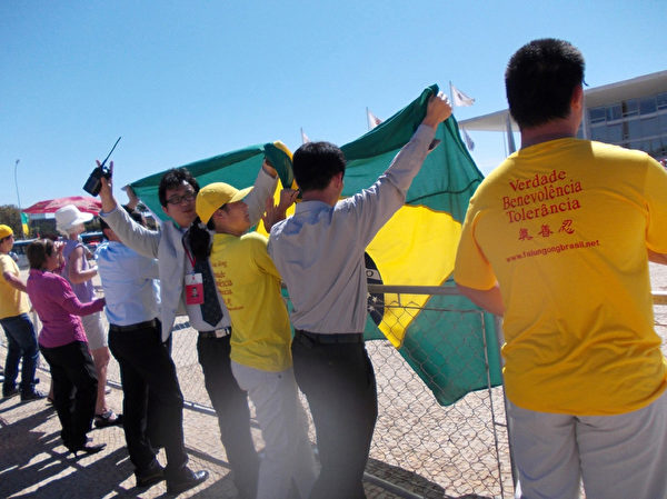 7月17日，法輪功學員們有秩序的於巴西總統府門前反對迫害，中共官員試圖蓋住抗議者卻毫無效果。（大紀元）