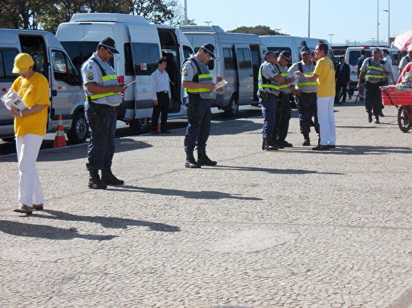 7月16日，中共保安指使巴西警方阻擋法輪功學員靠近習近平車隊，法輪功學員們給警察們發放真相資料。警察們仔細閱讀，中共保安束手無策。（大紀元）