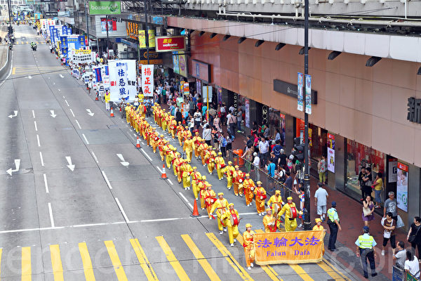 香港法轮功学员10月1日举行国殇日游行，8百多人的游行队伍途径多个闹市区，吸引不少市民驻足观看，有参与太阳伞学运的大学生高喊法轮大法好，也有大陆游客表示支持法轮功学员的信仰。（潘在殊/大纪元）