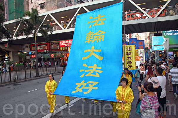 香港法轮功学员10月1日举行国殇日游行，8百多人的游行队伍途径多个闹市区，吸引不少市民驻足观看，有参与太阳伞学运的大学生高喊法轮大法好，也有大陆游客表示支持法轮功学员的信仰。（潘在殊/大纪元）