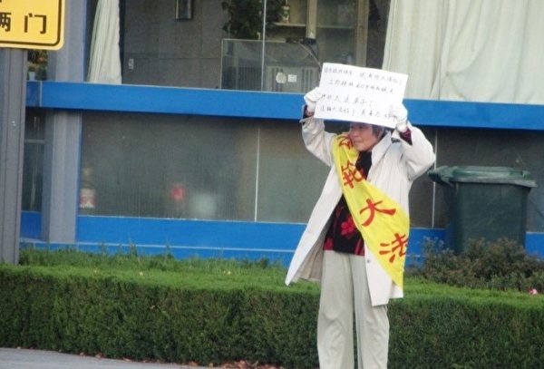 山東省龍口市法輪功學員吳曼萍為營救遭當局綁架的丈夫尹向陽，在龍口市委市政府舉牌抗議。（明慧網）