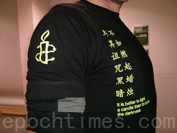 与会的国际大赦成员身穿写有中文的T恤，与其诅咒黑暗，不如燃起蜡烛。（文华/大纪元）