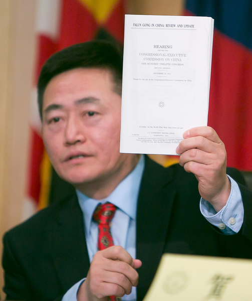 李祥春手举美国国会及行政当局中国委员会的报告，其中收录了他提交的中国退党大潮报告。（李莎/大纪元）