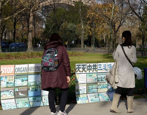 来巴黎旅游的中国大陆游客在景点观看真相板。（明慧网）