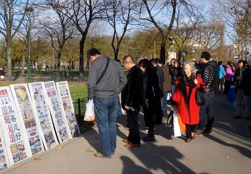中國遊客在巴黎景點觀看展板，瞭解真相。（明慧網）