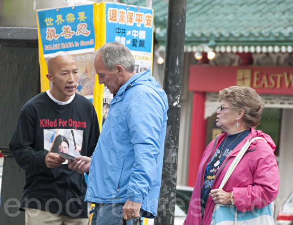 4月21日，华裔青年史蒂夫·马可(Steven Marcal,左）在旧金山中国城向游客、市民发放并讲述法轮功的真相。（周凤临／大纪元）