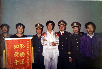 法轮功创始人（中）在北京传法。因对祛病健身具奇效，且能提高社会的道德水平，1999年7月20日前法轮功在大陆获得很多政府与民间组织的褒奖。（明慧网）