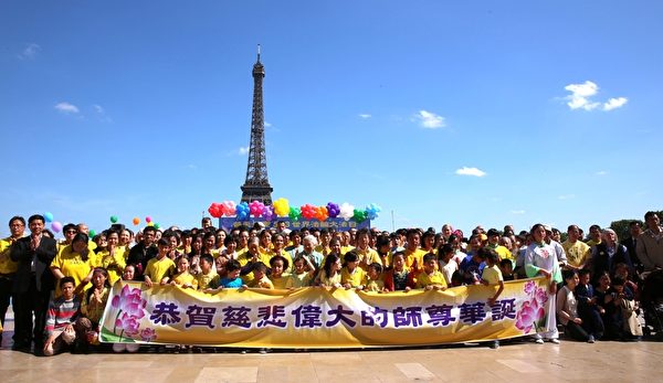 法國巴黎法輪功學員聚集在艾菲爾鐵塔前，慶祝法輪大法洪傳世界二十三週年，並向李洪志師父祝賀生日快樂。（大紀元）